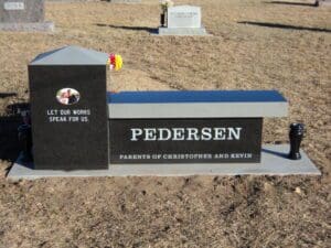 Bench-style cemetery headstone with flowers