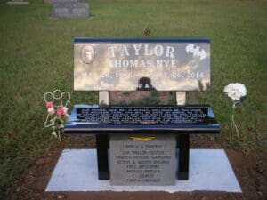 Black memorial bench gravestone with flowers