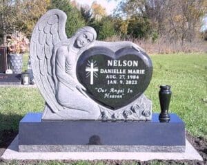 Angel statue leaning on heart-shaped gravestone