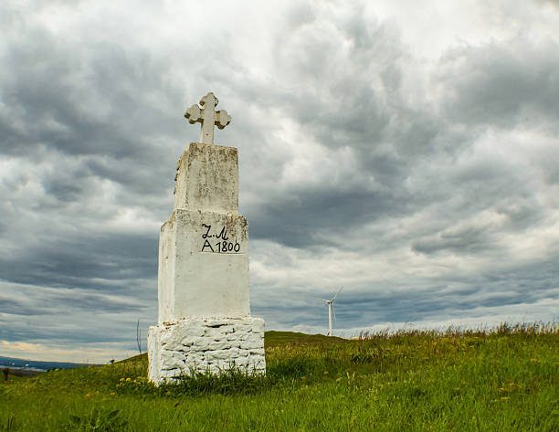 White stone cross monument in grassy field