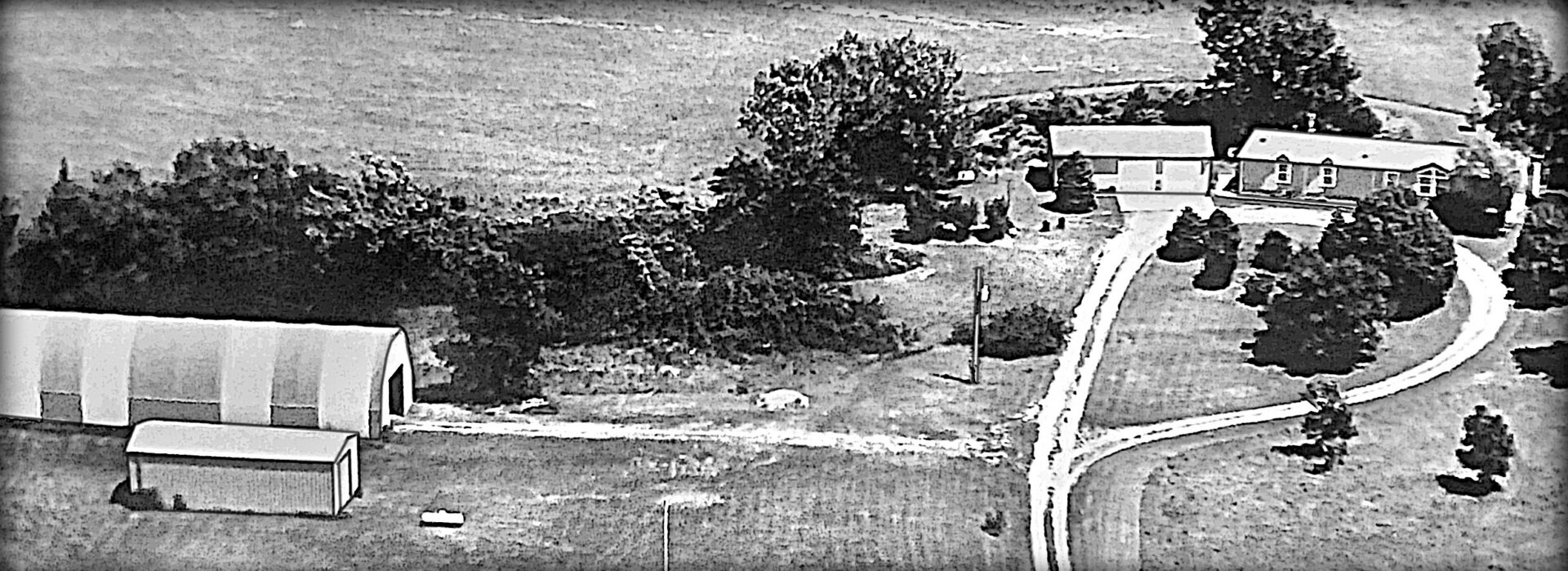 Aerial view of a rural home and sheds.