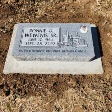 Gray gravestone with truck illustration and inscription.